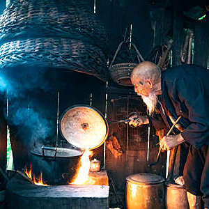Old Chinese senior man cooking water in simple kitchen. 