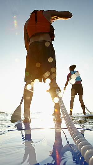 Man and woman riding on stand-up paddle boards.