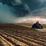 Tornado-chasing vehicle with IMAX camera drives along ploughed fields towards a looming storm in Colorado, USA
