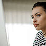 Young woman with headphones looks absorbed as she participates in a distance-learning course.