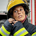 Female firefighter putting on helmet.