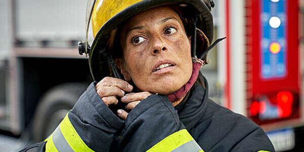 Female firefighter putting on helmet.