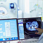 Male doctor running CT scan from control room at hospital